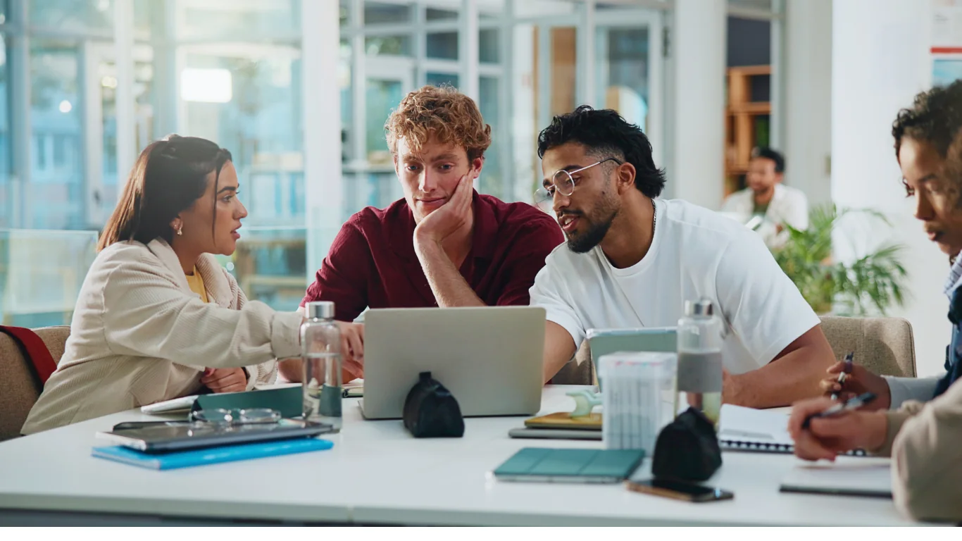 Quatre étudiants réunis autour d'une table avec un ordinateur portable pour organiser leur projet de groupe