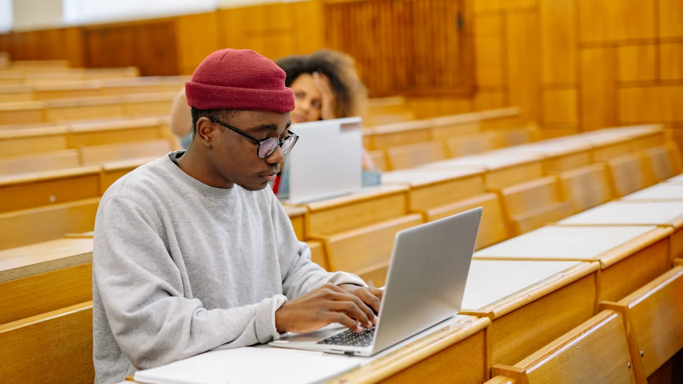 Étudiant assis dans un auditorium, travaillant sur son ordinateur portable pour trier ses sources et ses citations